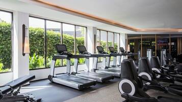 A gym with treadmills, weight machines, and dumbbells.