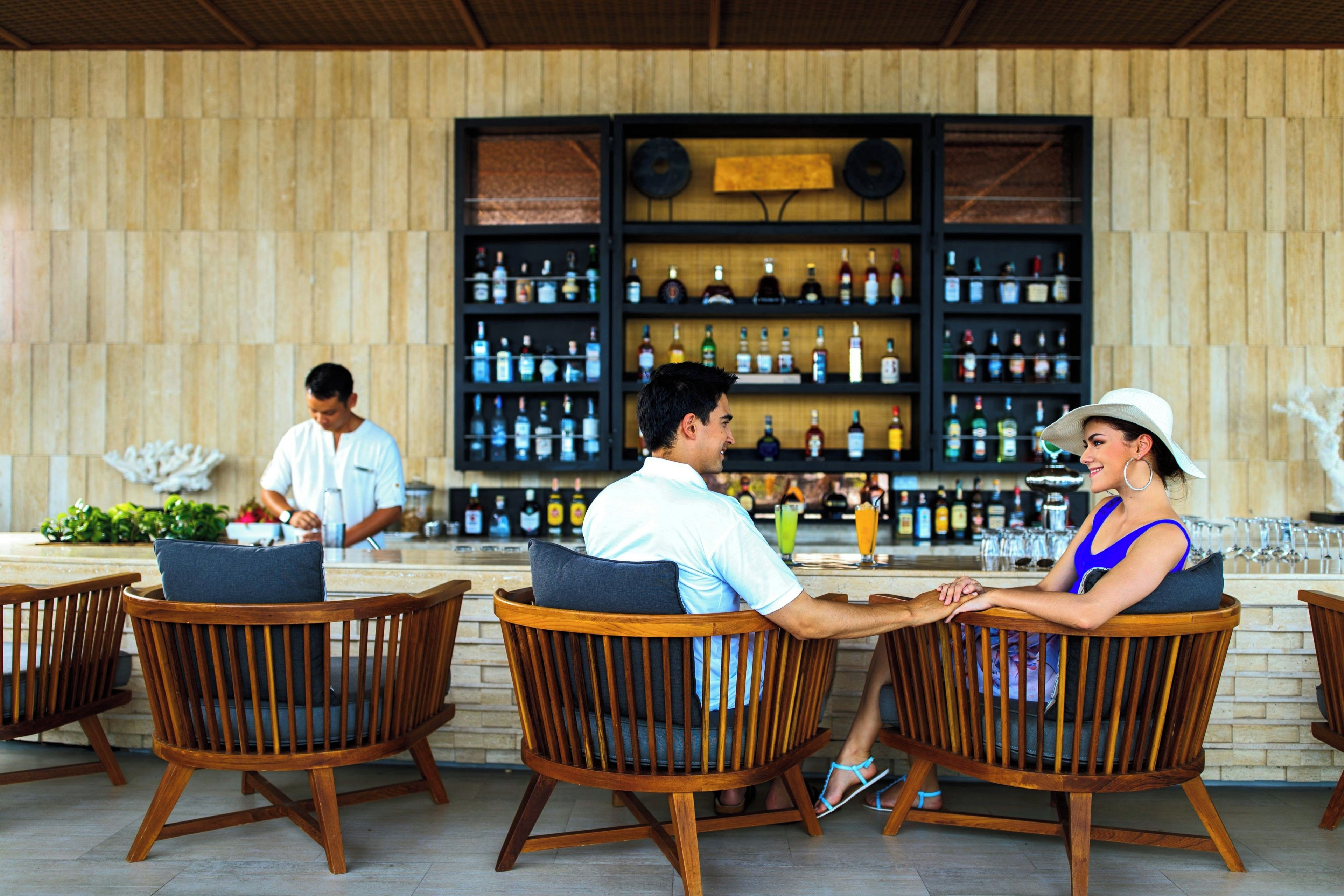 A bar area with wooden chairs and a bartender.