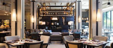 A modern restaurant interior with a bar area, multiple seating arrangements, and hanging pendant lights.