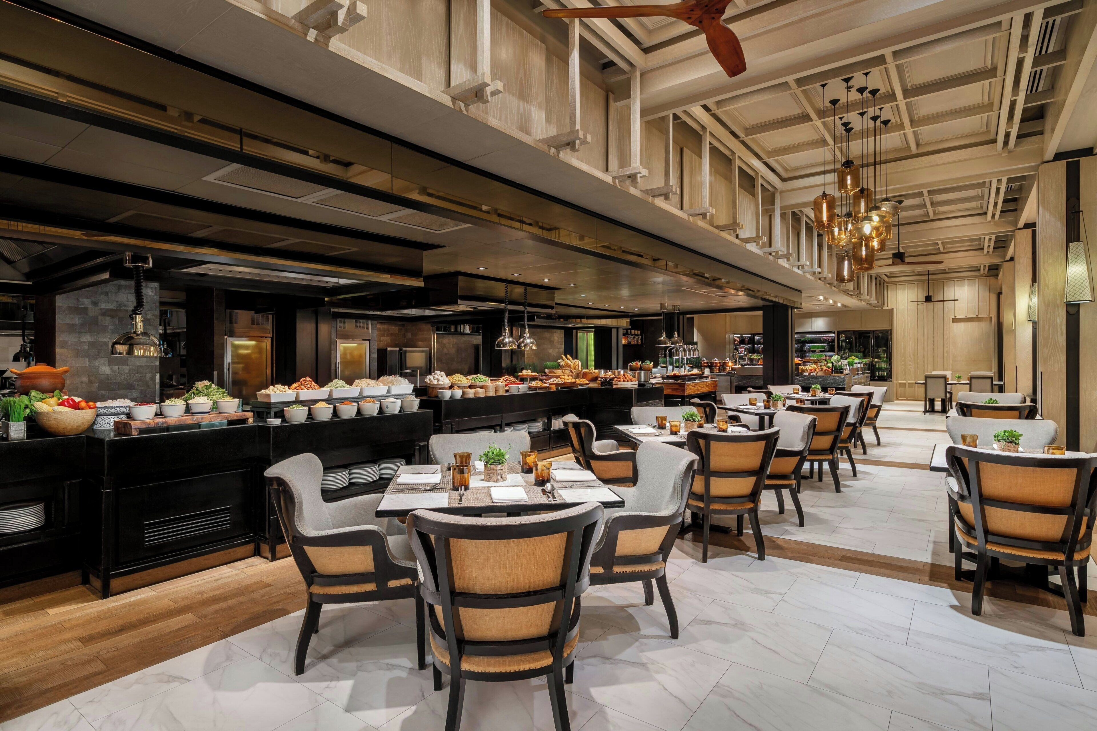 A spacious restaurant with high ceilings, modern lighting, and a variety of seating arrangements.