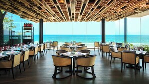 Een restaurant met gedekte tafels, met uitzicht op een schilderachtig zeegezicht.