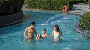 Una piscina con un elemento acuático, rodeada de vegetación.