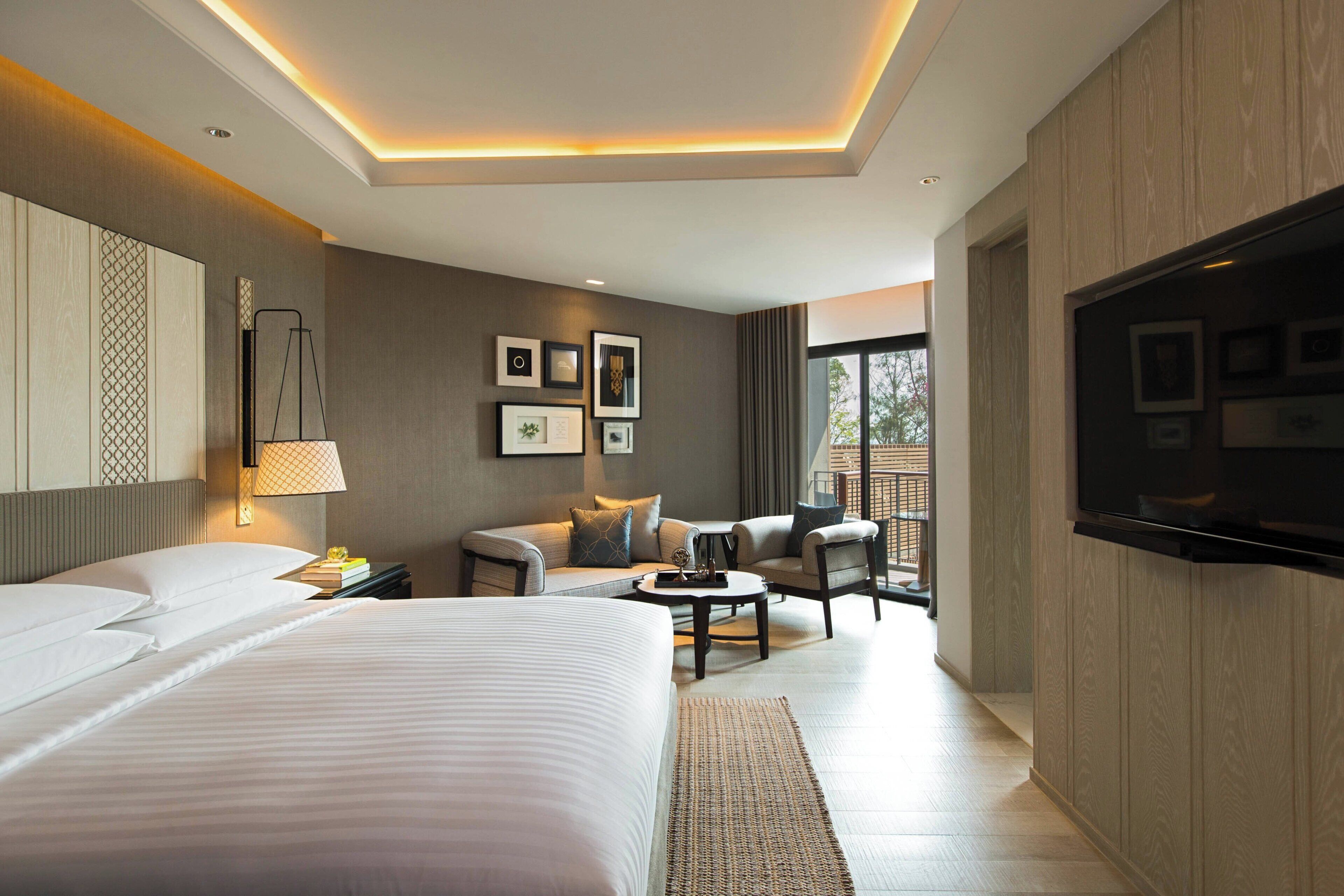 Een moderne hotelkamer met een groot bed, een sofa, een televisie en een bureau.