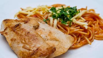En tallerken med grillet kylling og spaghetti med pynt.