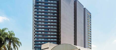 Un hotel moderno con un llamativo letrero de 'ibis Hotel', un amplio estacionamiento y un edificio 'ibis Novel' cercano.