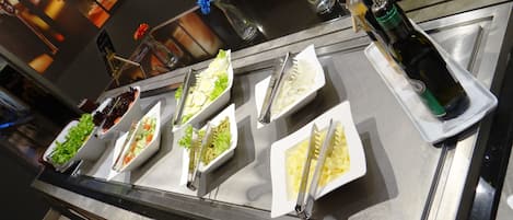 Un mostrador de buffet con diversos alimentos y utensilios.