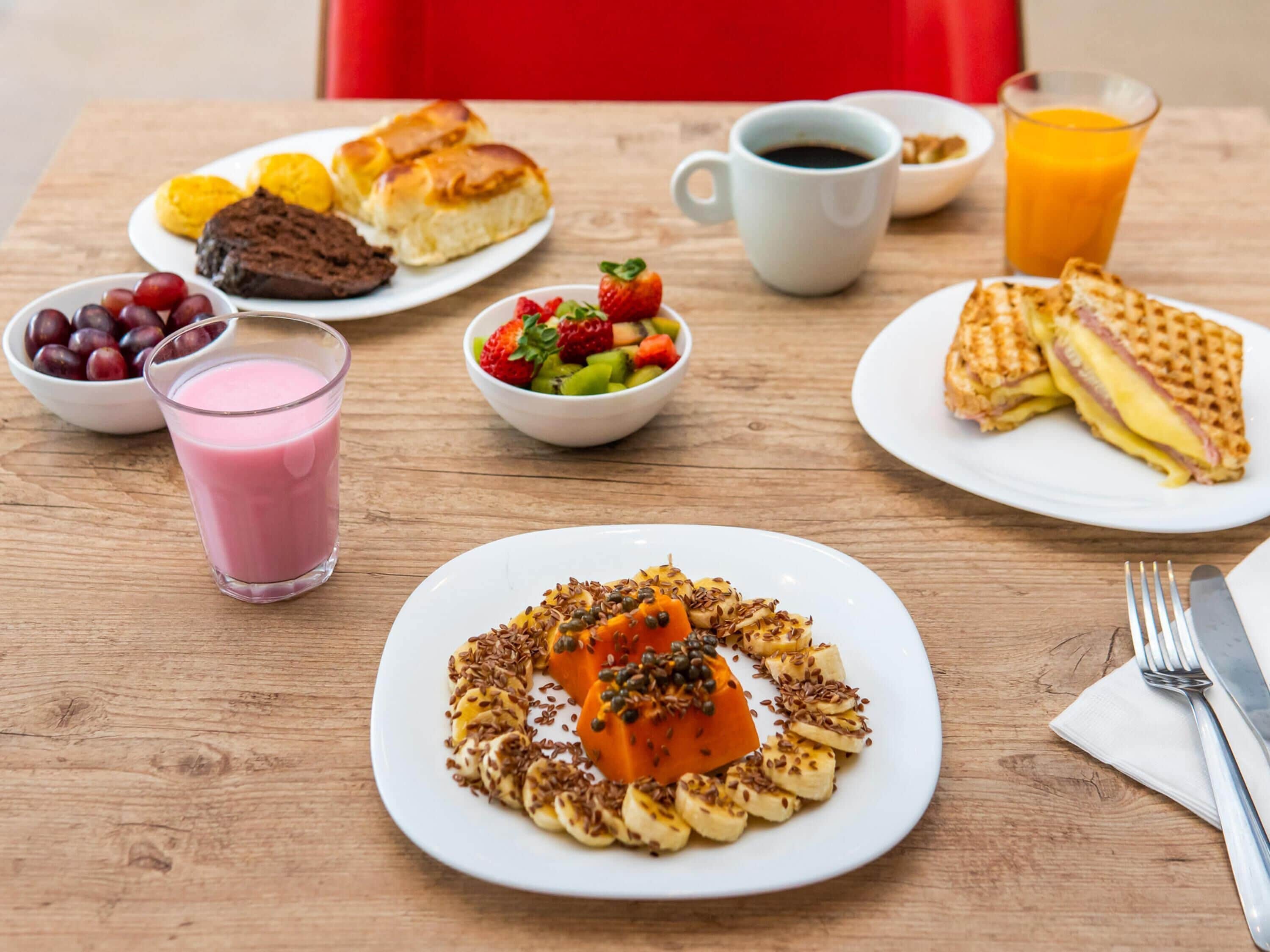 A breakfast table with plates of food, a glass of juice, and a cup of coffee.