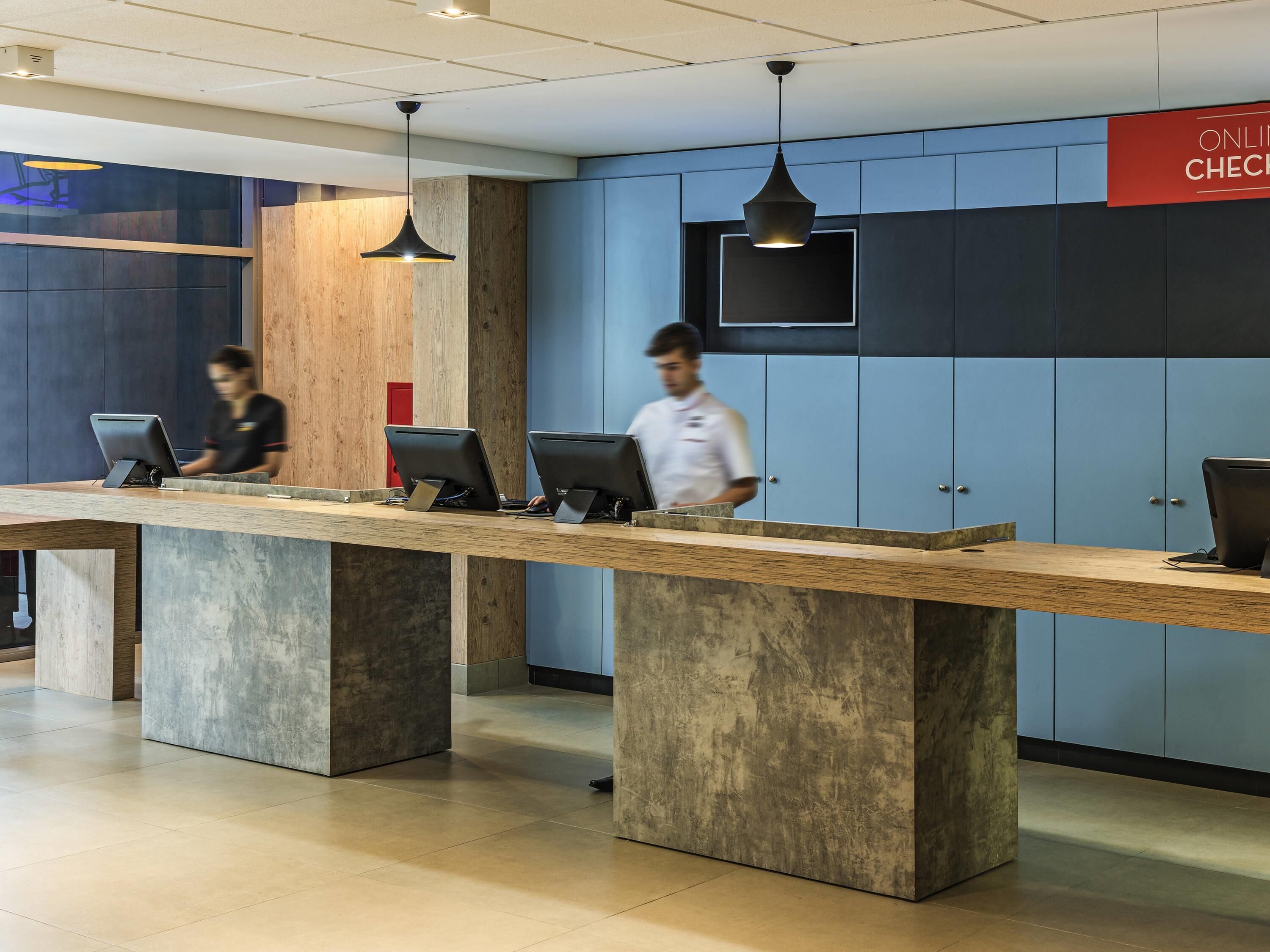 A reception desk with computers, a sign for online check-in, and a blue wall with lockers.