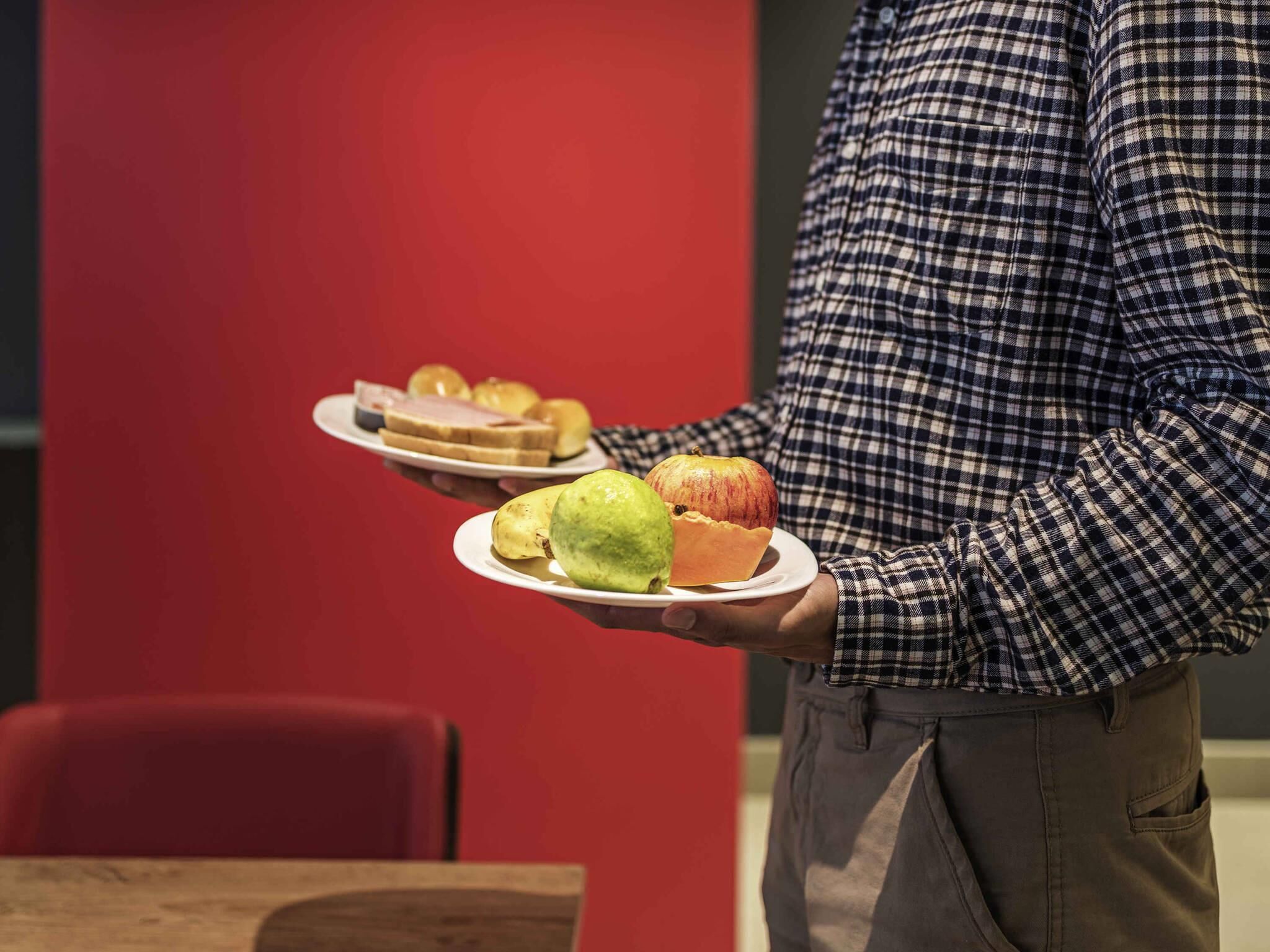 A person holding plates with food items.