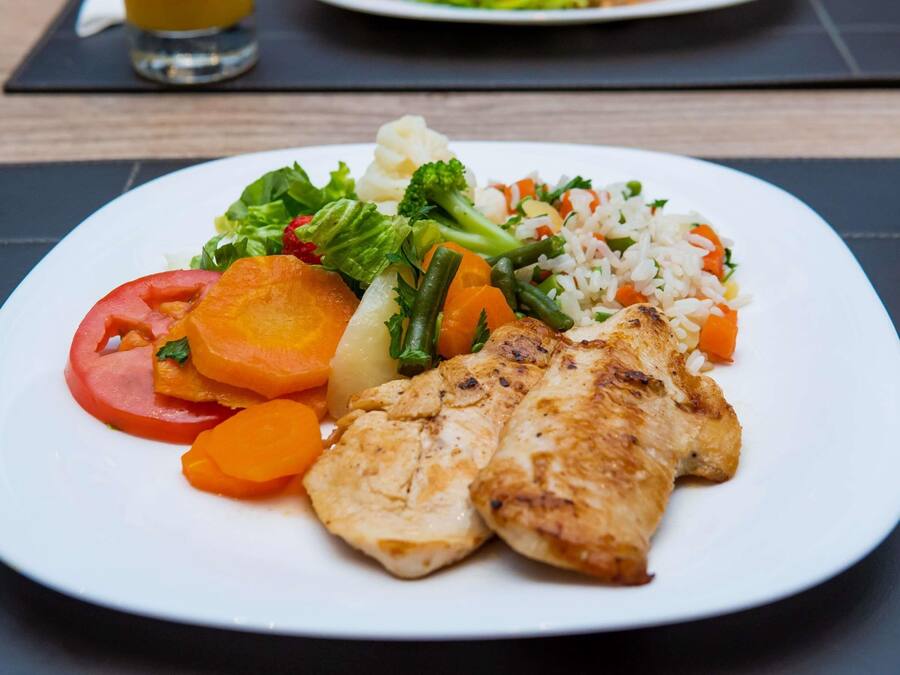 Un plato con pollo a la parrilla, verduras y arroz.