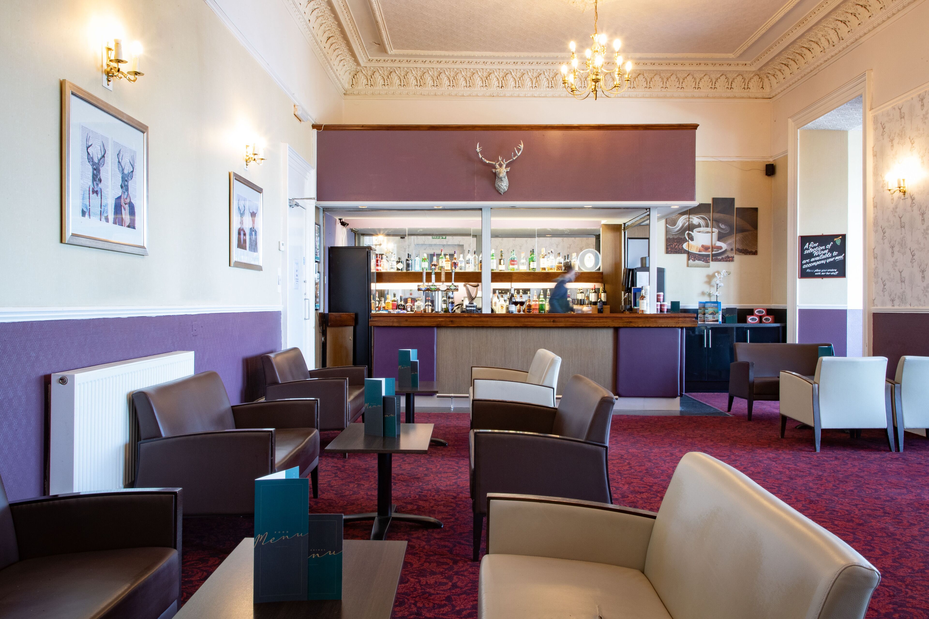 Een hotel lobby met zithoeken, een bar en een open haard.