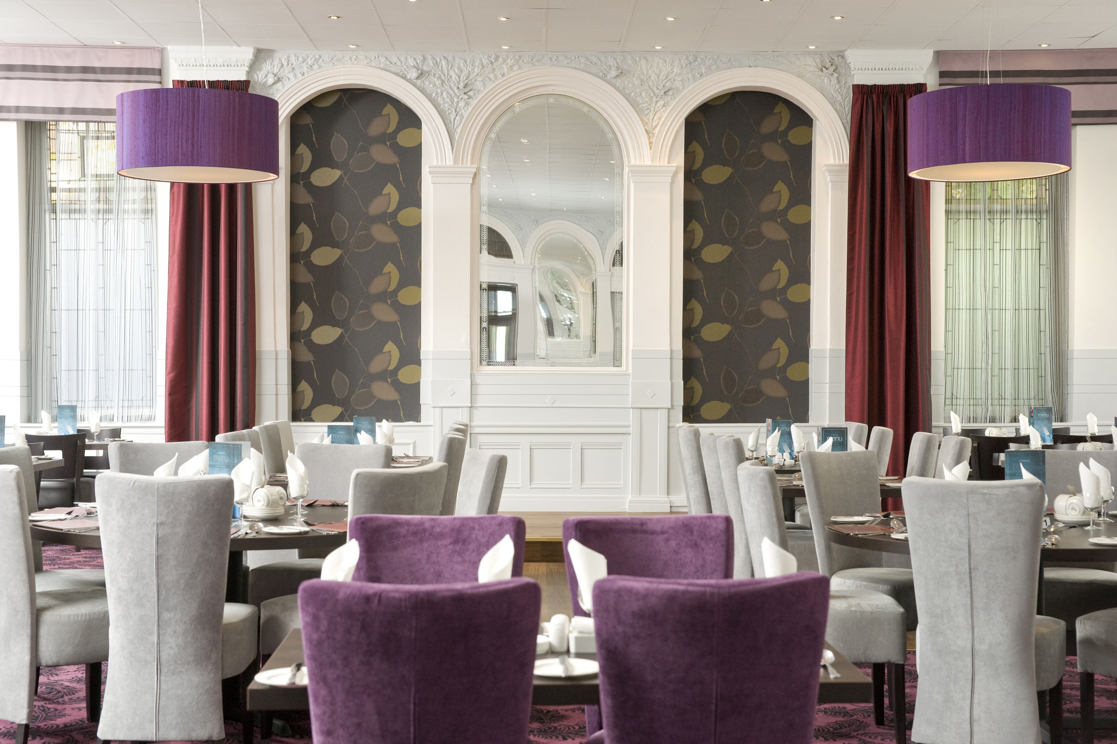 Un restaurant avec une salle à manger aménagée de façon élégante, comprenant plusieurs tables et chaises, ainsi qu’un arc décoratif central.