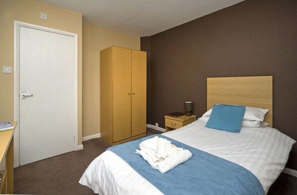 A hotel room with a bed, a wardrobe, a bedside table, and a nightstand.