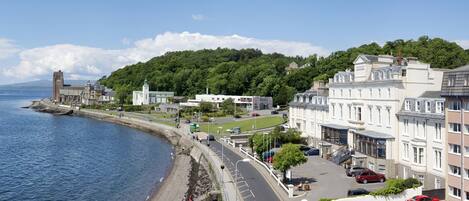 A coastal town with a historic building, a church, and residential buildings along a waterfront.