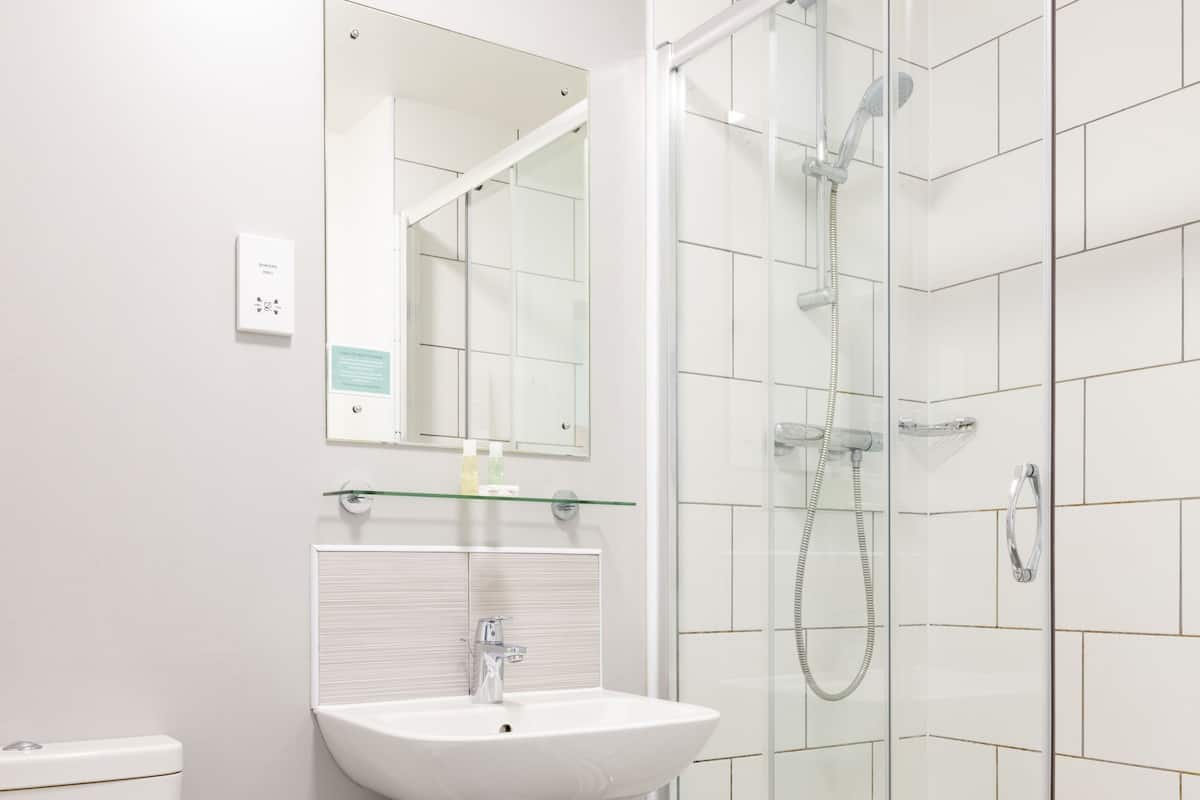 A modern bathroom with a glass-enclosed shower, a white sink, and a toilet.