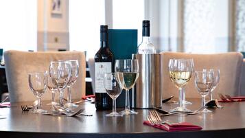 A dining table set with wine glasses, a wine bottle, and a silver thermos.