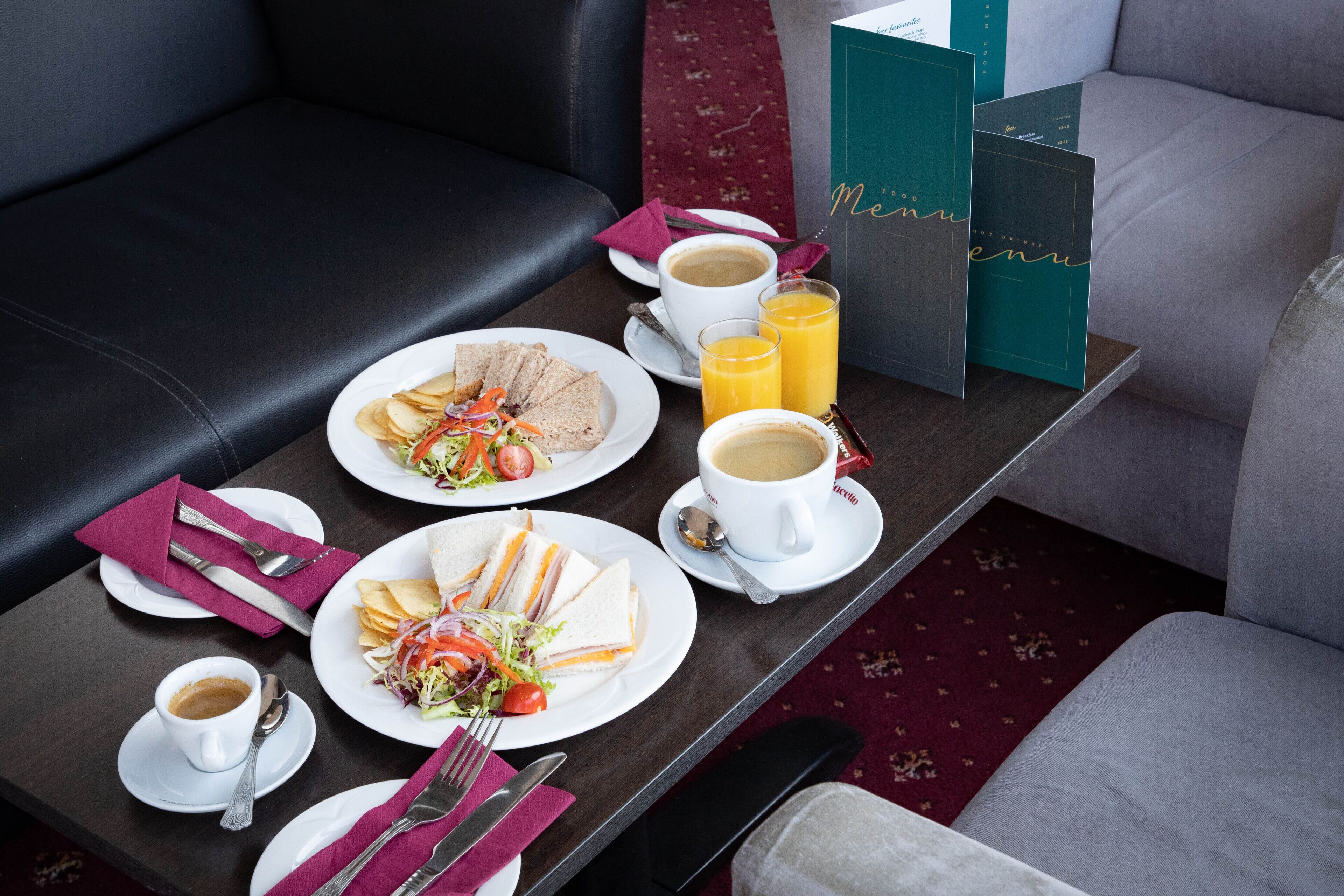 A dining table with plates of food, cups of coffee, and juice glasses.