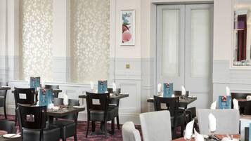 Un restaurante con una lámpara colgante morada, papel tapiz floral y un gran arco de entrada.