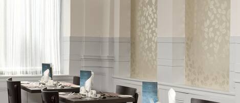 A dining area with tables set for four, each with a menu stand, plates, glasses, and cutlery.