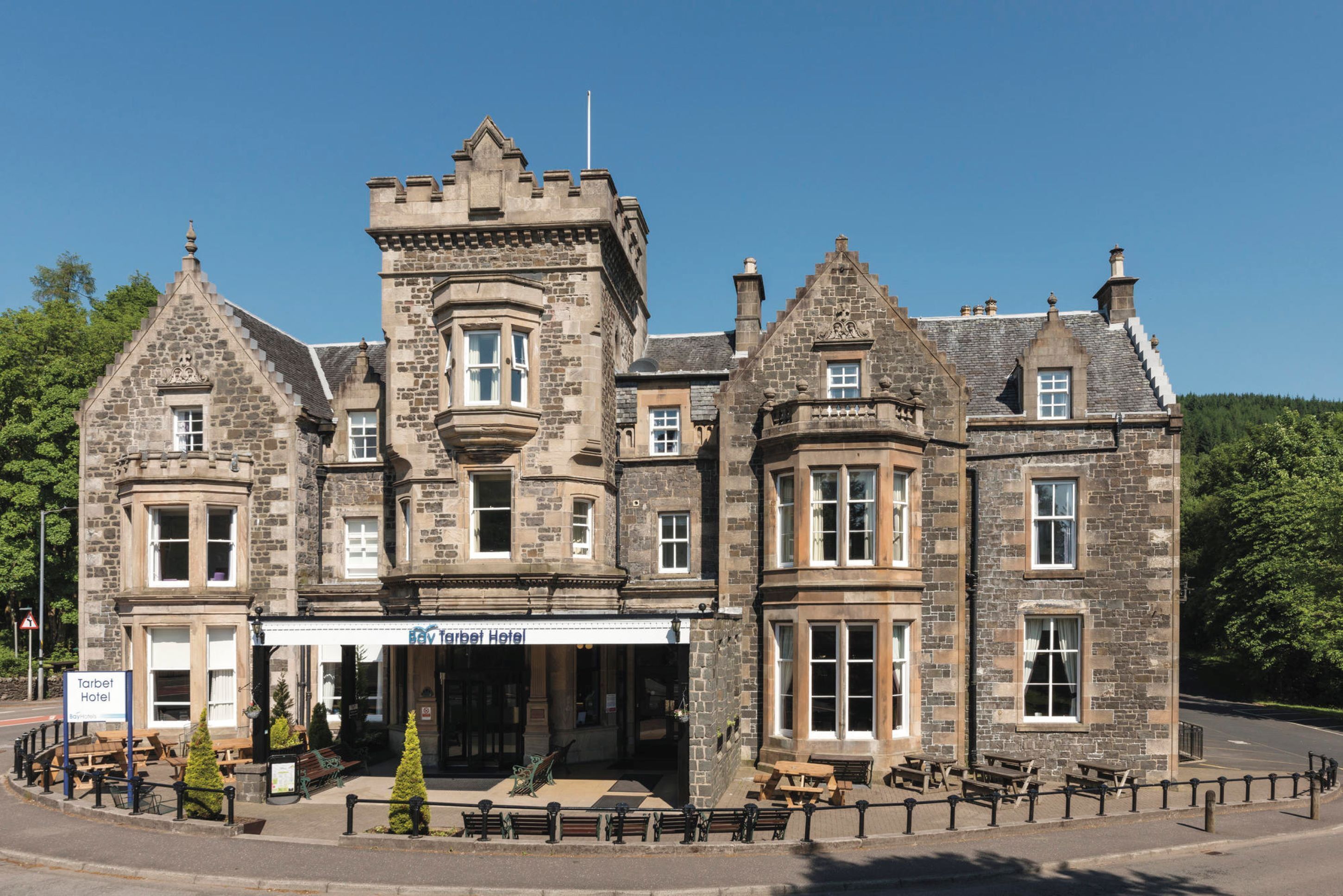 A historic stone building with a corner turret, a bay window, and a sign for the Tarbert Hotel.