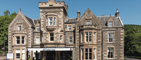 A historic stone building with a corner turret, a bay window, and a sign for the Tarbert Hotel.