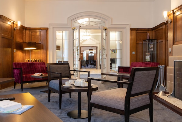 Un vestíbulo de hotel con mostrador de recepción, zona de estar y vista al comedor.