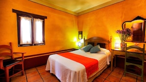 A hotel room with a bed, a chair, a desk, and a window with curtains. - Hotel Azucena (Oaxaca)