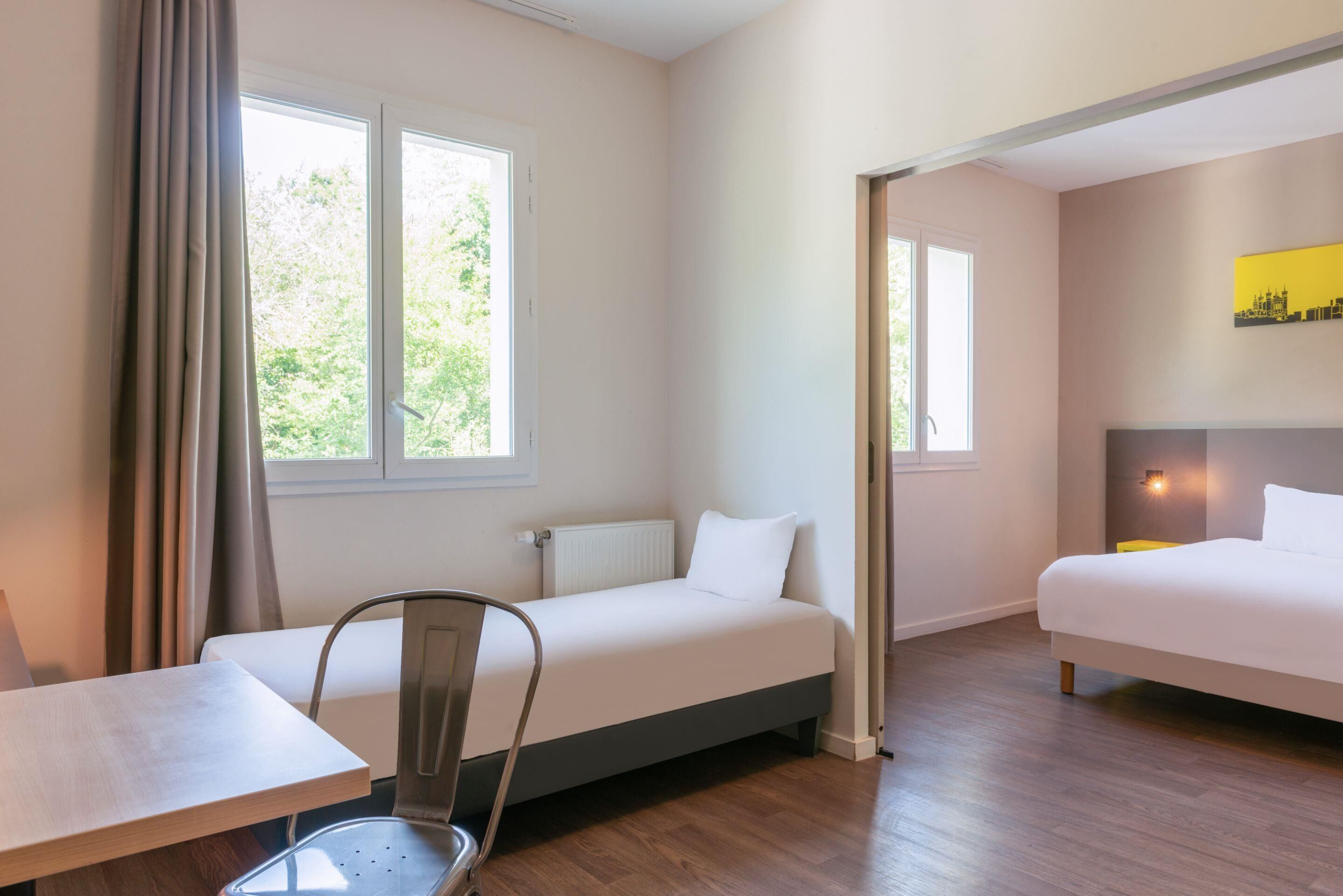 Una habitación de hotel con dos camas, una mesa de comedor y una silla.