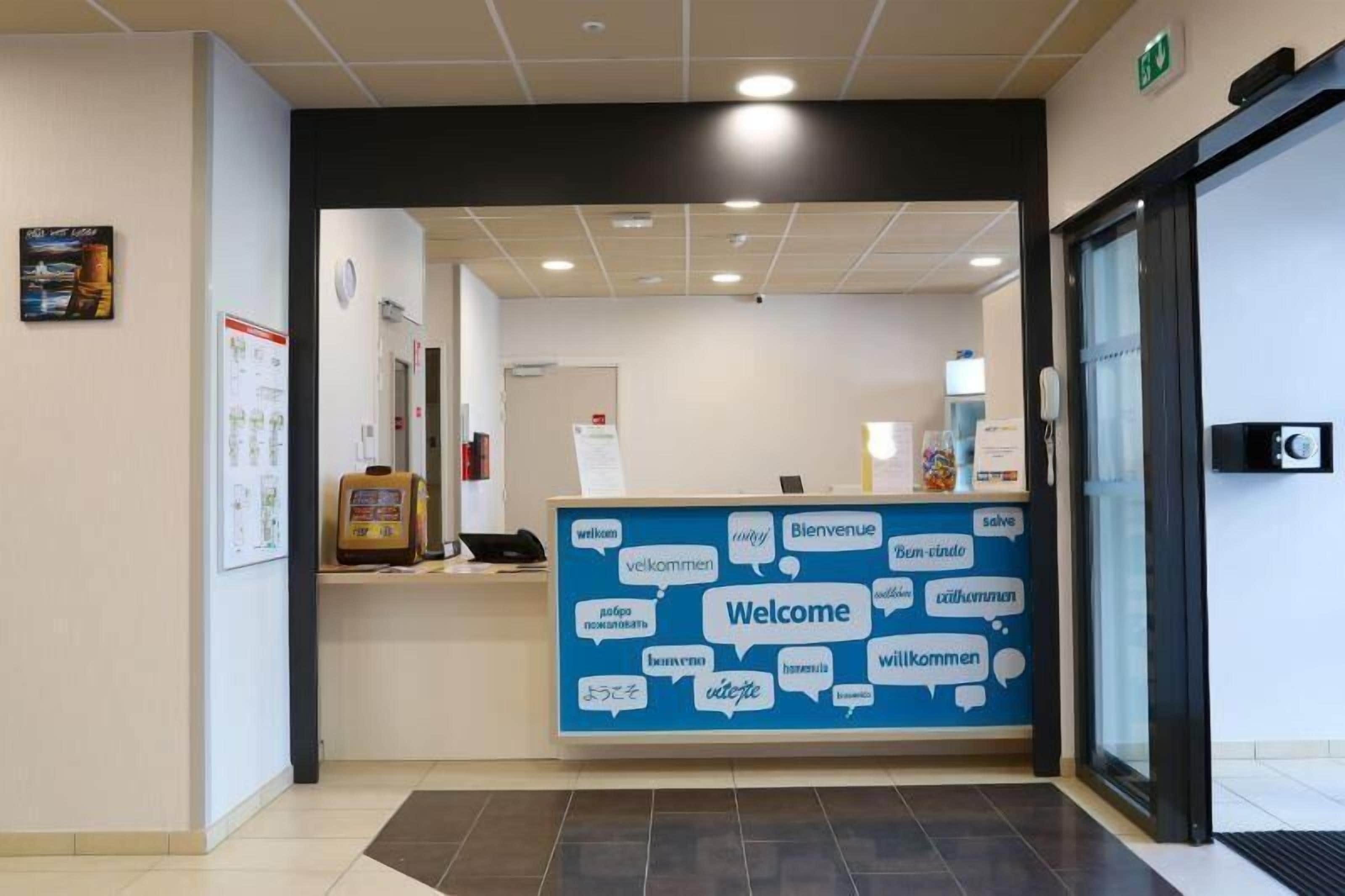 A reception area with a blue 'Welcome' sign featuring multiple language options.
