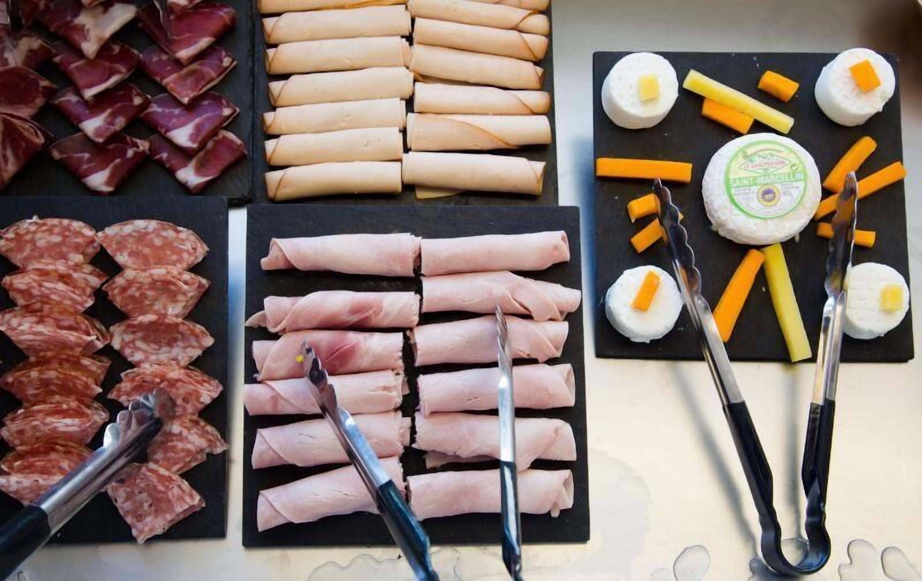 A variety of food items including cured meats, sausages, and cheese arranged on a board.