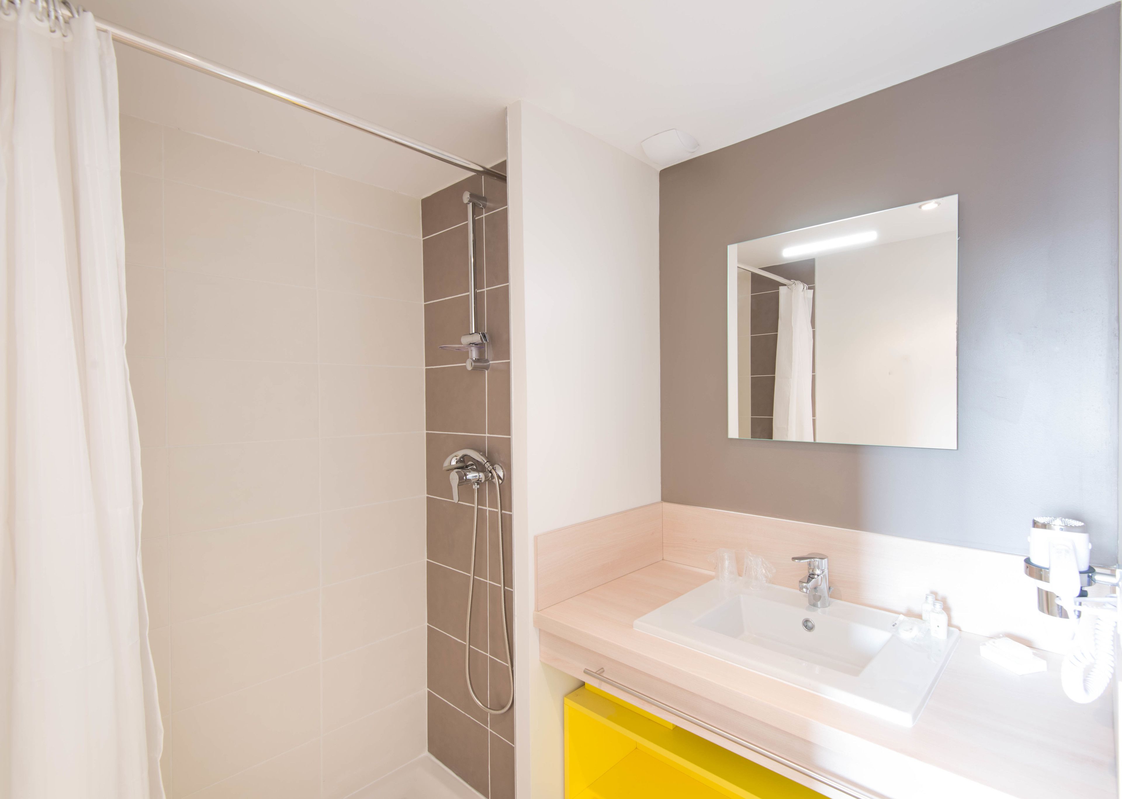 Un baño moderno con ducha, lavamanos y espejo.