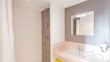 Een moderne badkamer met een douche, een wastafel en een spiegel.