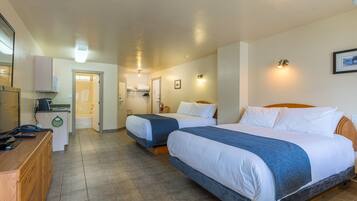 A hotel room with two beds, a desk, a mirror, and a bathroom visible through an open door.