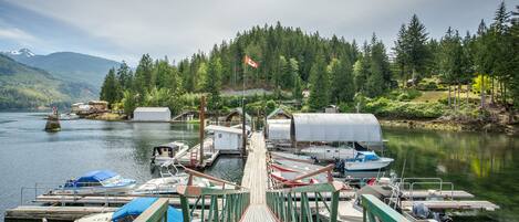 A dock with boats, a covered structure, and a forested hillside.