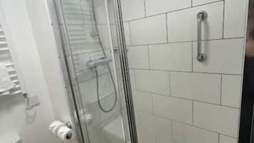 A shower enclosure with a glass door, a toilet, and white tiled walls.