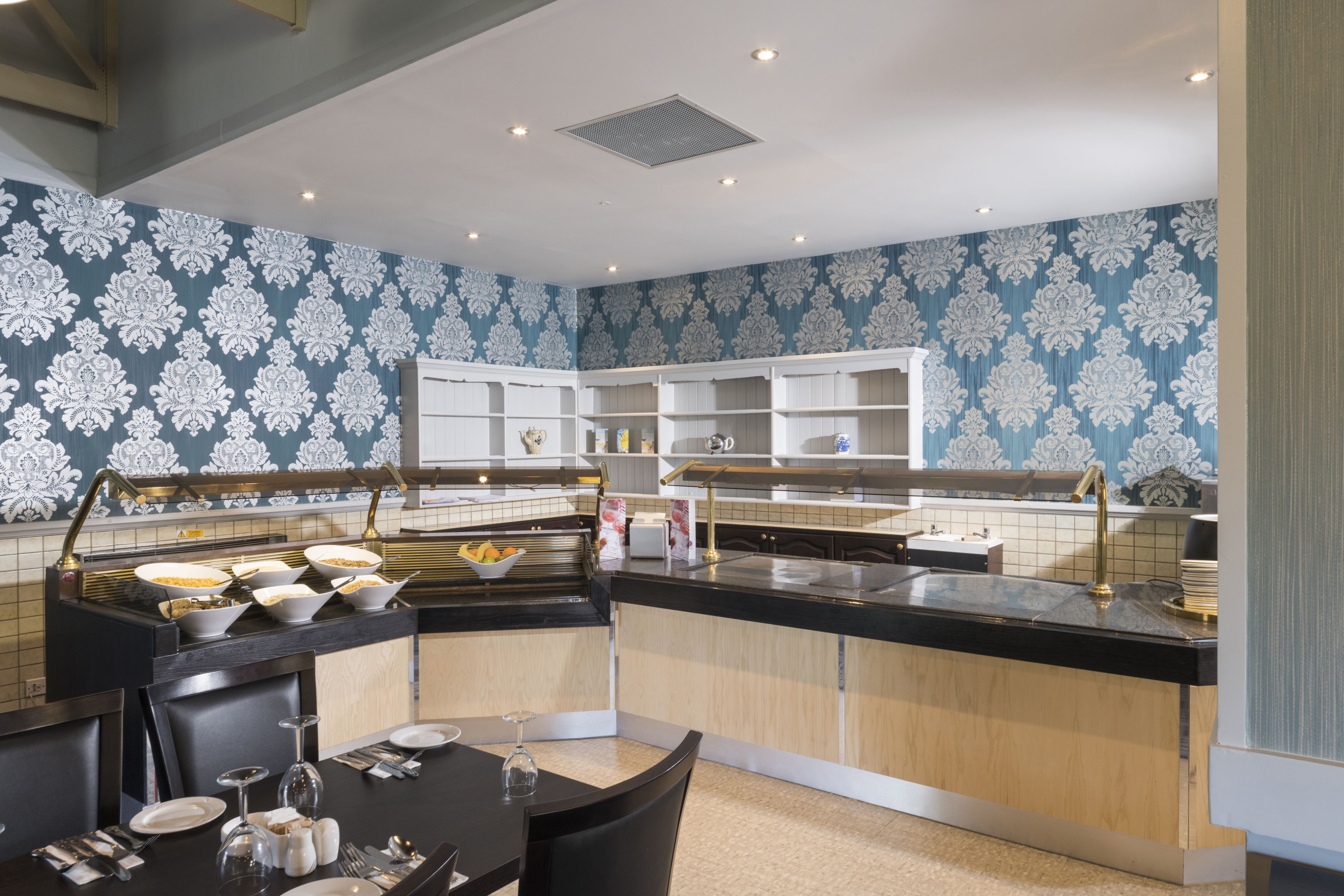 A modern kitchen with a black countertop, white cabinetry, and a blue patterned backsplash.