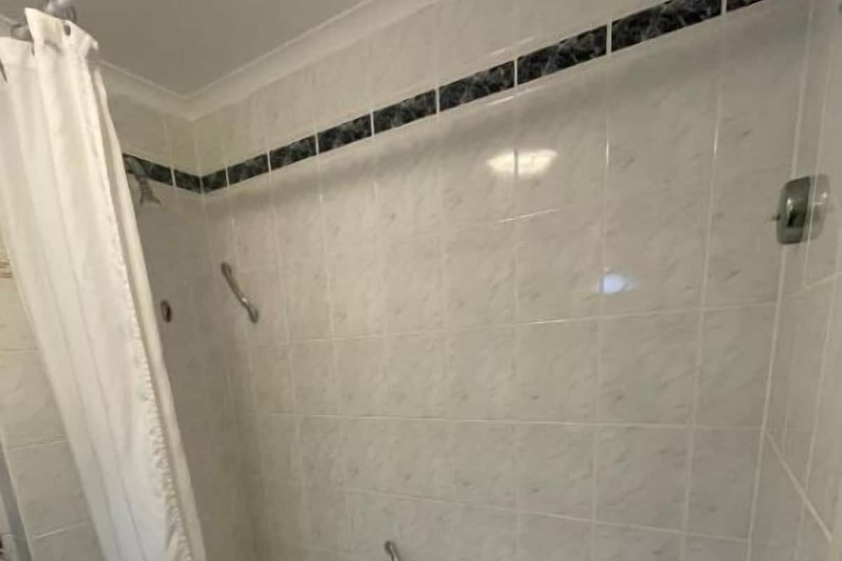 A bathroom with a bathtub, a shower curtain, and tiled walls.