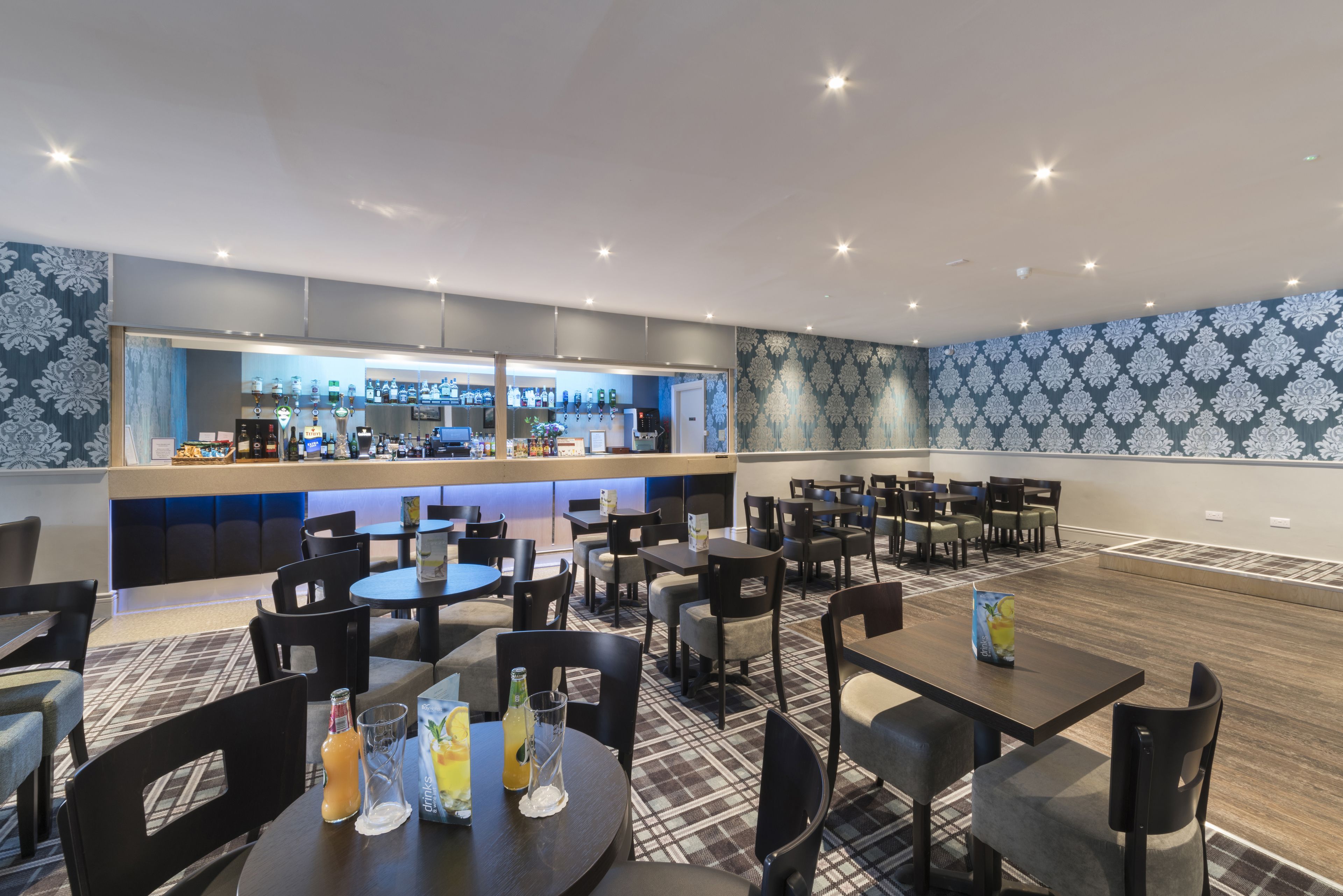 A modern restaurant with a bar area, multiple seating options, and a patterned wall design.