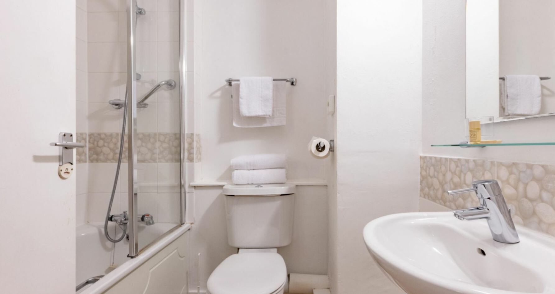 A bathroom with a glass-enclosed shower, a toilet, and a sink with a mirror.
