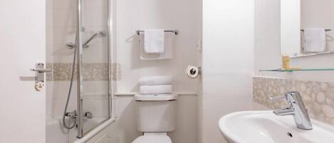 A bathroom with a glass-enclosed shower, a toilet, and a sink with a mirror.