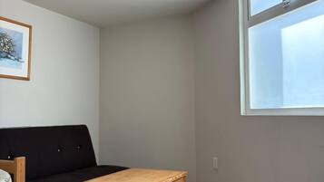 A room with a black sofa, a wooden table, and a window.
