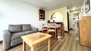 A living room with a grey sofa, a wooden table, and a kitchen area with a microwave and sink. - Privada 400 Casas & Suites (Pachuca)