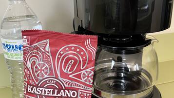 A coffee maker, a water bottle, and a packet of coffee creamer.