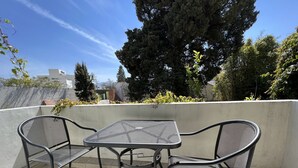 A rooftop terrace with a metal table and two chairs, surrounded by a low wall and greenery. - Privada 400 Casas & Suites (Pachuca)