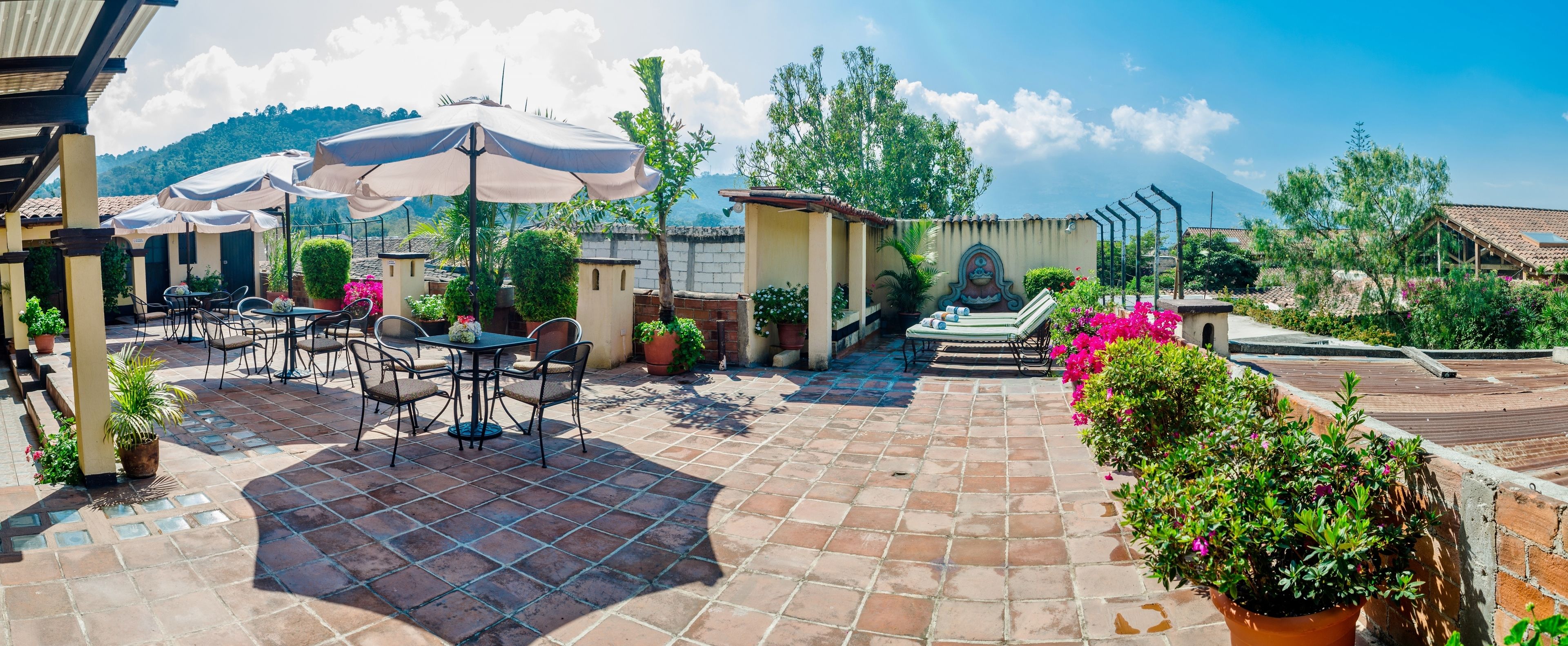 An outdoor patio with tiled flooring, outdoor seating, and potted plants.