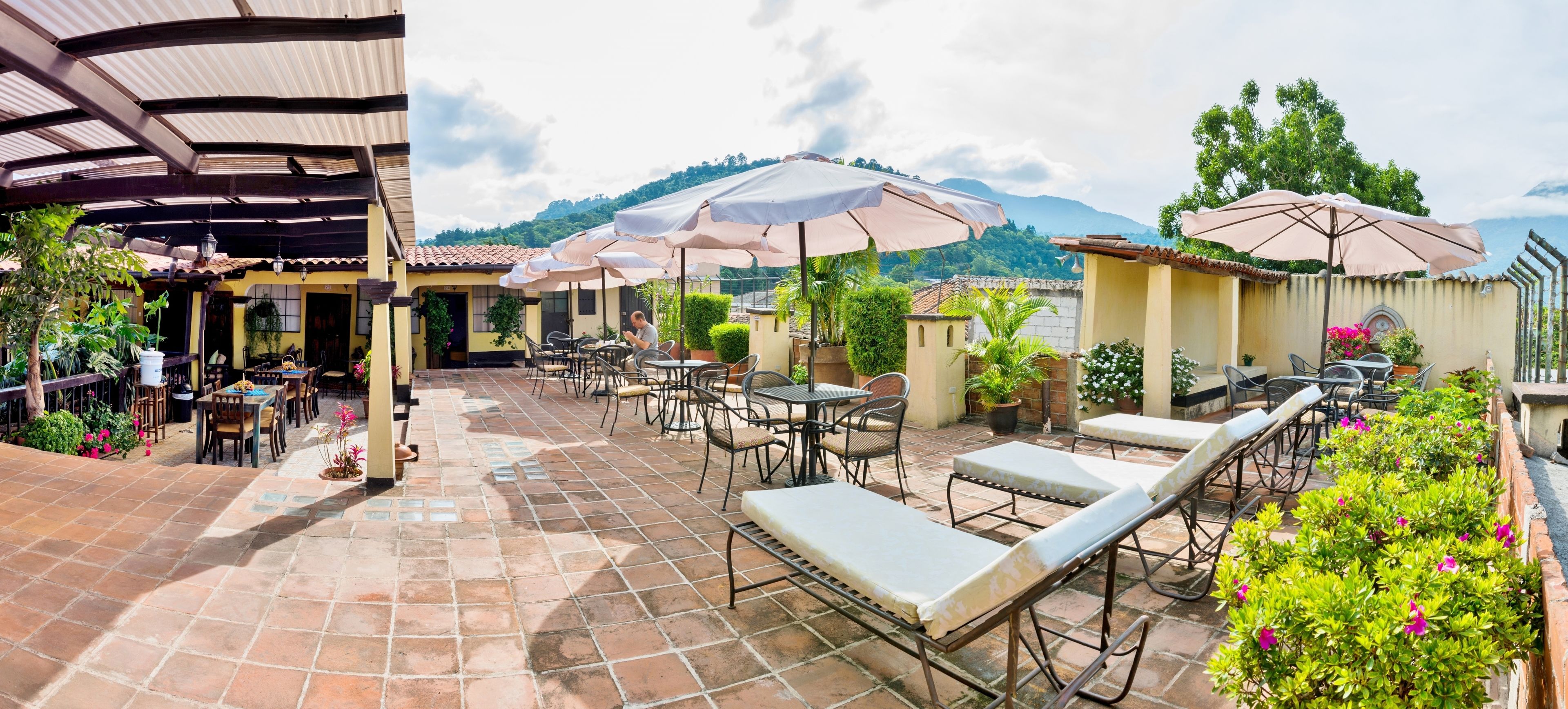 A patio area with outdoor seating, umbrellas, and potted plants.