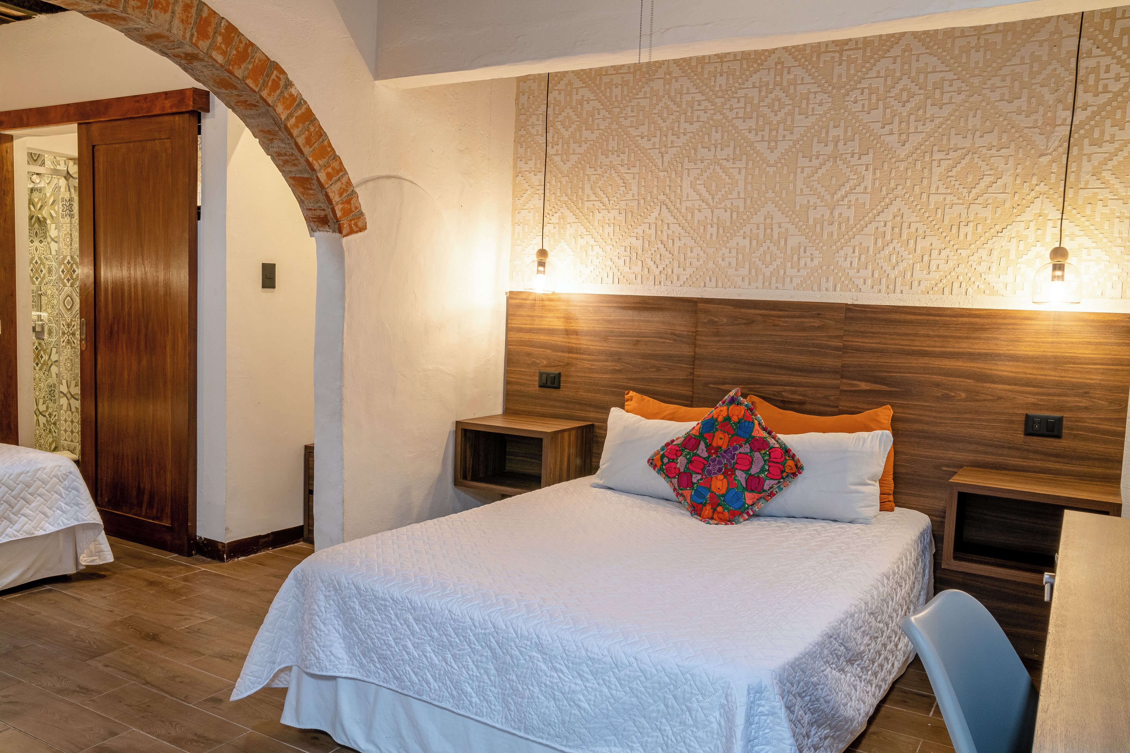 A bedroom with a large bed, wooden headboard, two bedside tables, and a nightstand.