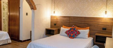 A bedroom with a large bed, wooden headboard, two bedside tables, and a nightstand.