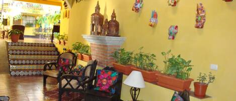 A cozy interior with a tiled floor, wooden furniture, and a variety of potted plants.