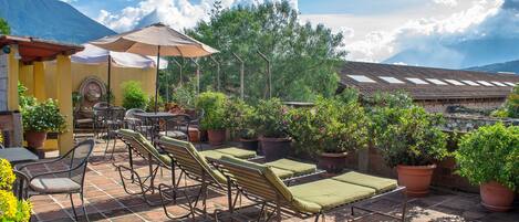 An outdoor patio with lounge chairs, tables, and potted plants.
